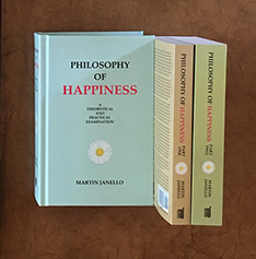 Photo of the hardcover and the 2-part paperback of the Philosophy of Happiness book showing front and spines on desk.