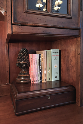 Photo of all 9 in print books about Philosophy of Happiness authored by Martin Janello on a wooden bookshelf.