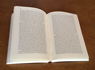 Photo of interior text of the opened Philosophy of Happiness book, Paperback Part Two, on desk.